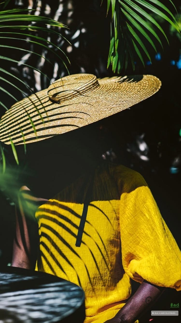 Portrait en vêtement jaune, avec un large chapeau et des ombres de feuillage.