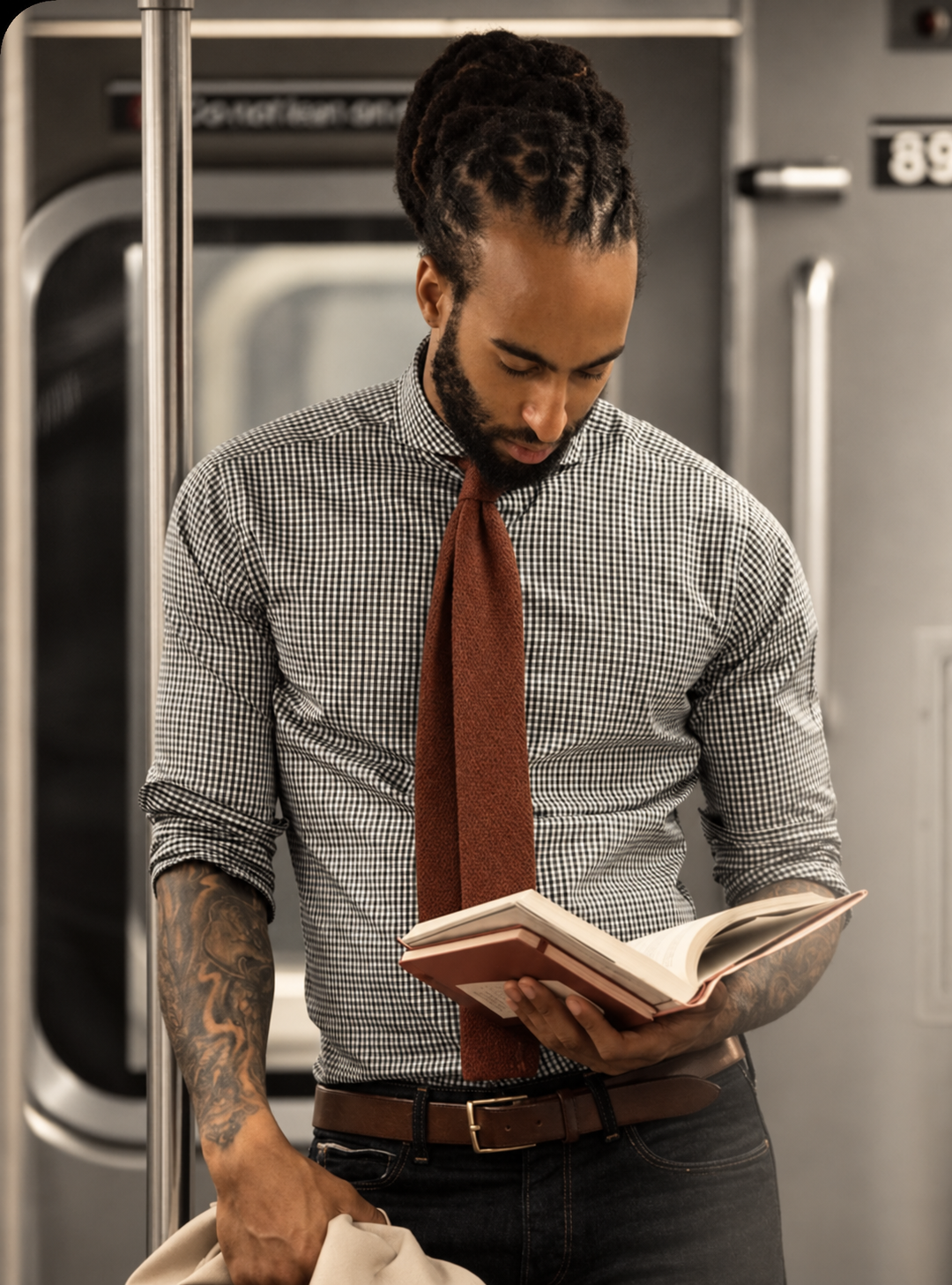 Un homme lit un livre dans un train, dans des tons sobres rehaussés de terracotta et de crème.